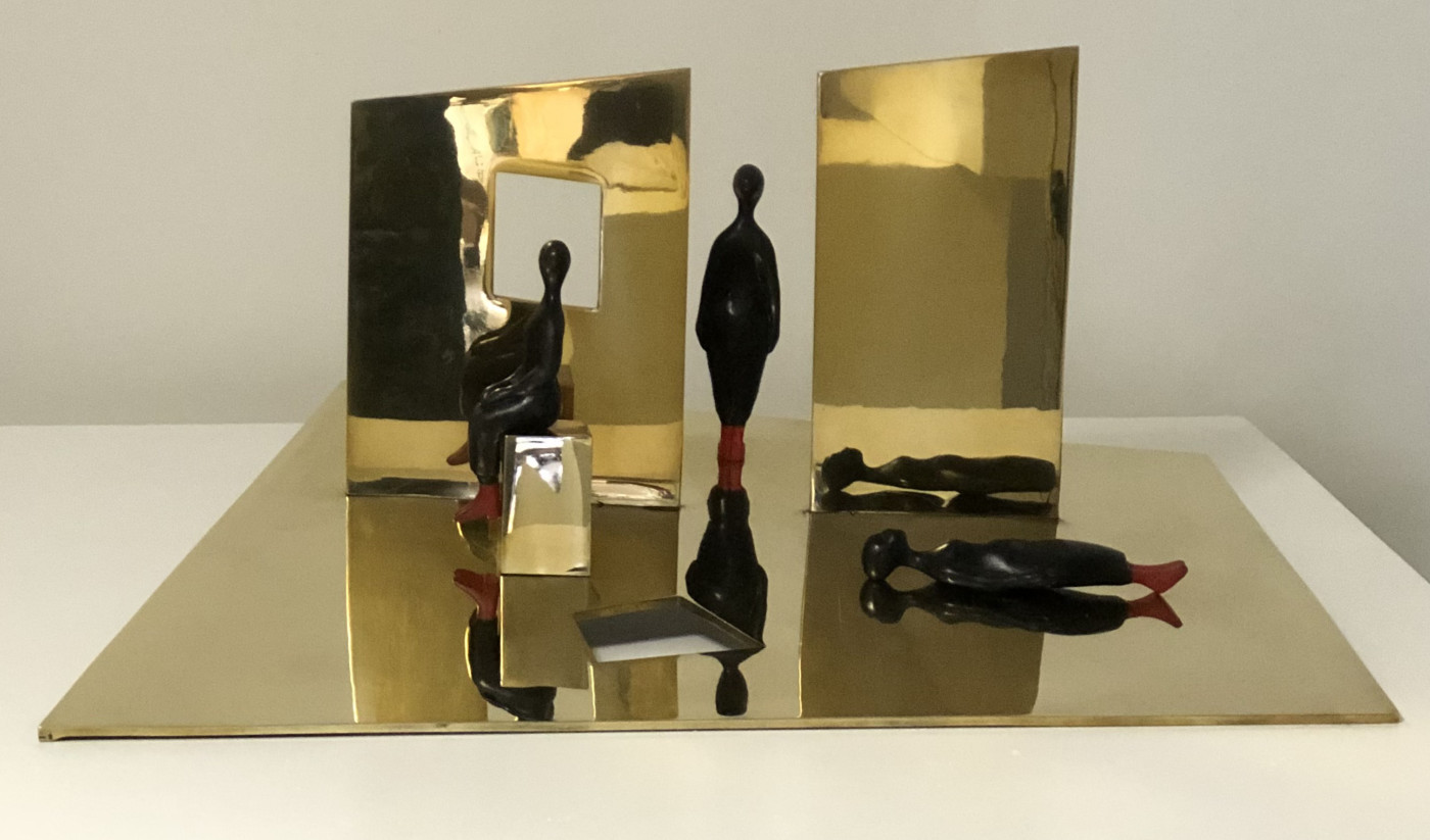 polished bronze sculpture of figures with abstract housing